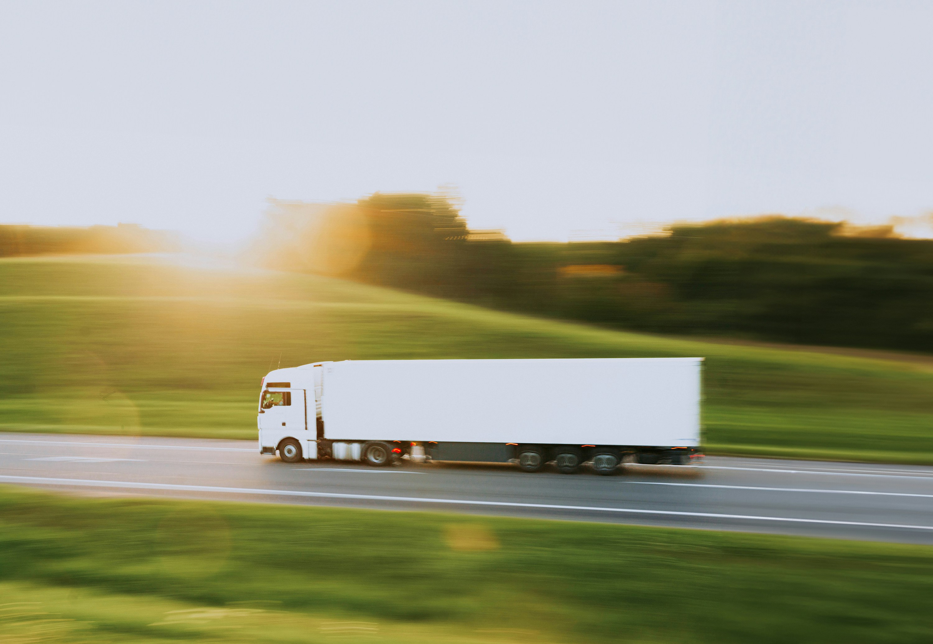 Duża ciężarówka transportowa jadąca nowoczesną autostradą, symbolizująca transport towarów i usługi logistyczne.